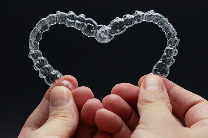 hands holding dental aligners in heart shape on bl 2023 02 28 18 33 53 utc